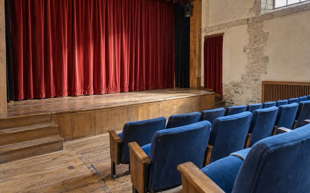 Salle de théâtre vide aux rideaux vermillon.